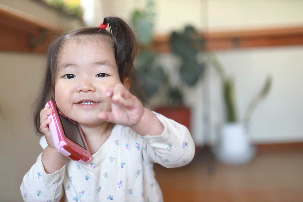 スマホ型おもちゃで遊ぶ子ども
